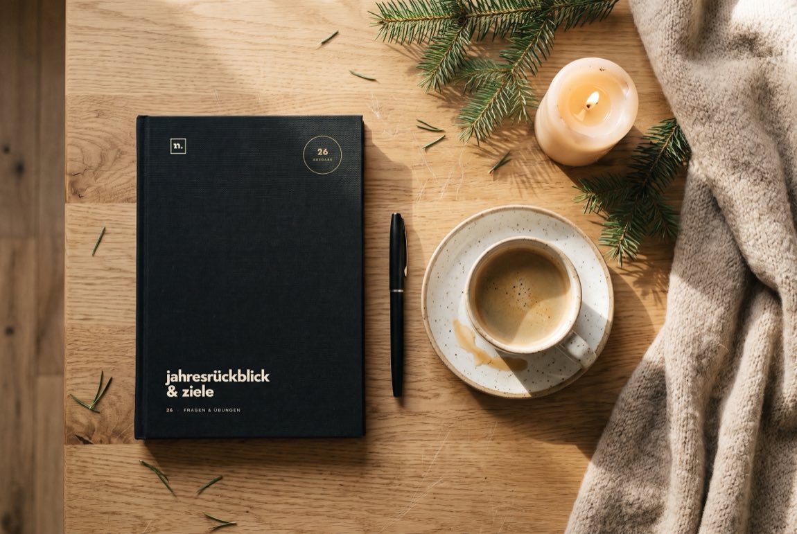 Die Ausgabe 26 liegt mit Stift, Kaffee, brennender Kerze und Tannenzweigen auf einem hellen Holztisch