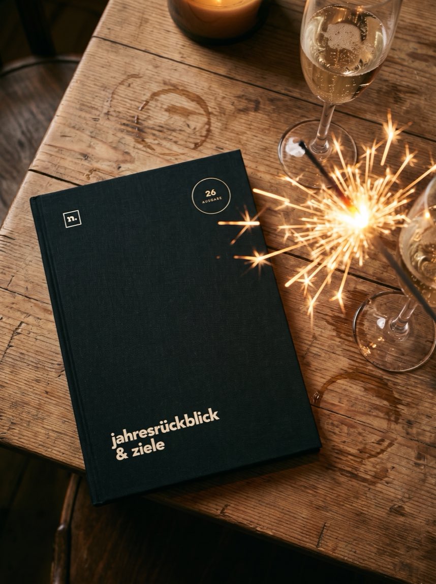 Die Ausgabe 26 neben zwei Sektgläsern und einer Wunderkerze am Silvesterabend